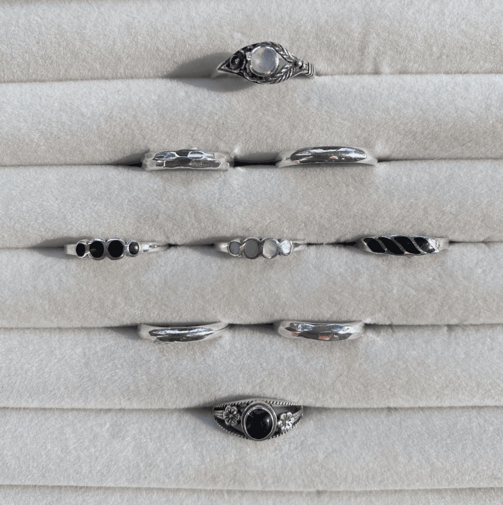 an assortment of gemstone rings including moonstone, onyx, mother of pearl, and sterling silver bands